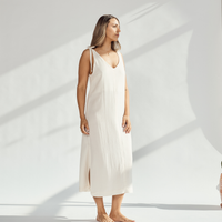 Elegant soft cotton dress with tied straps and leg slits, worn by a woman standing gracefully.