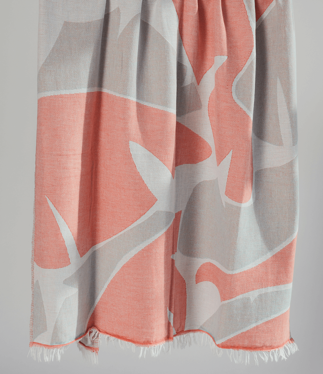 Turkish beach towel in coral and gray patterned with fringed edges