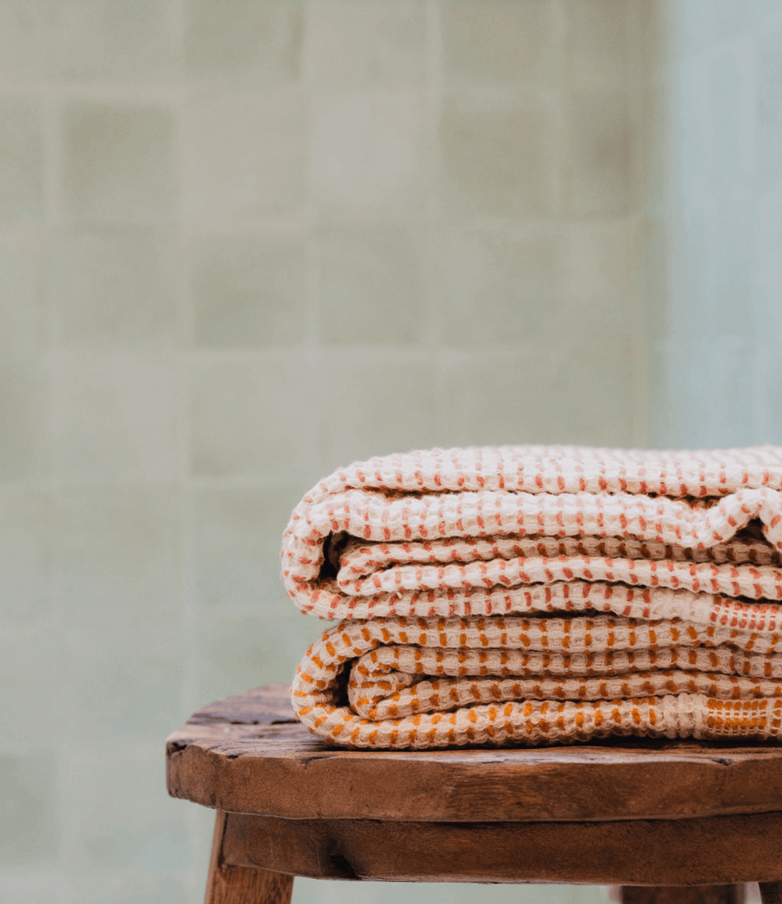 Two "Kalkan" beach towels folded on top of a stool