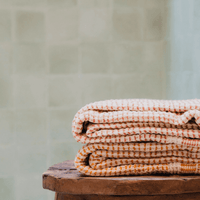 Two "Kalkan" beach towels folded on top of a stool