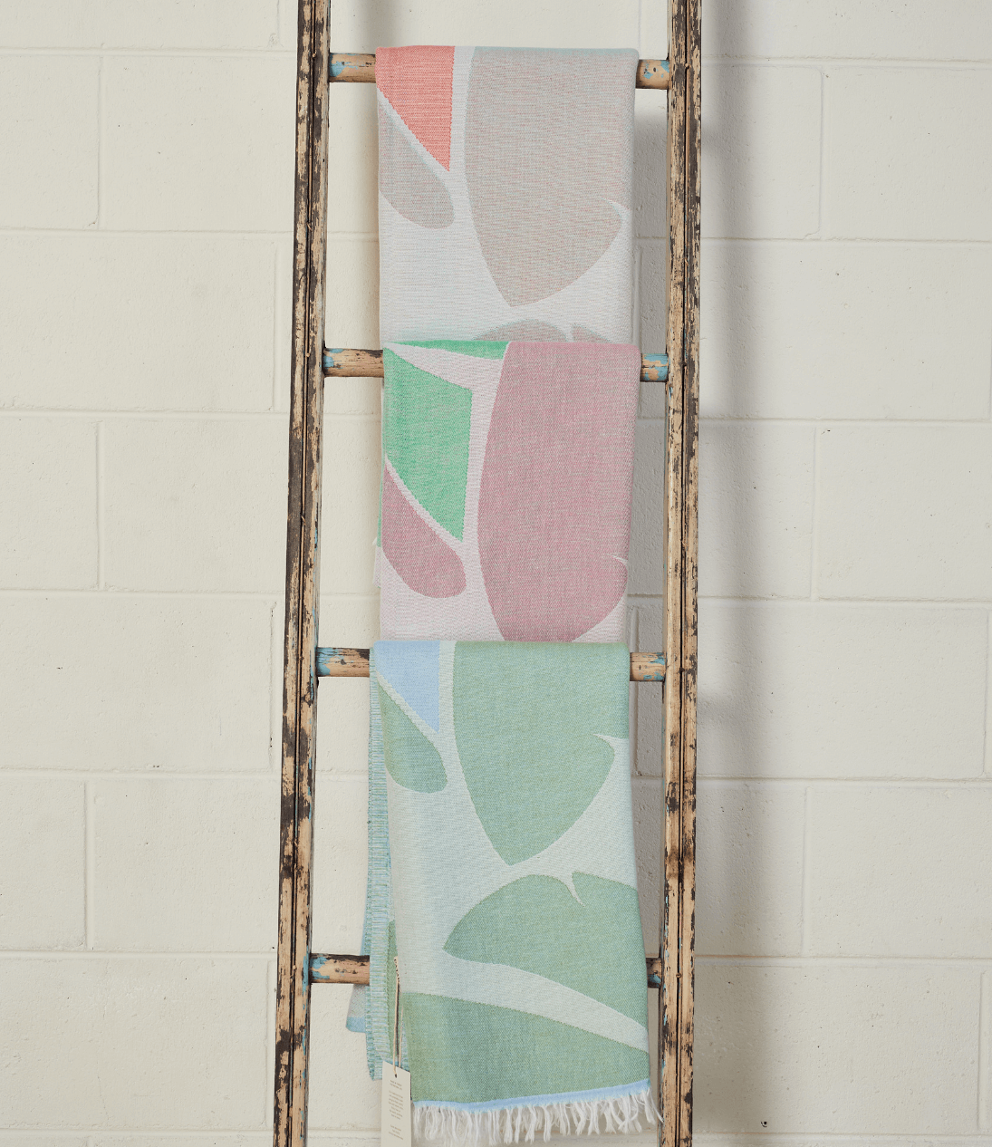 Pastel Coloured Turkish Beach Towels showcasing leaf patterns hanging on a rustic ladder.