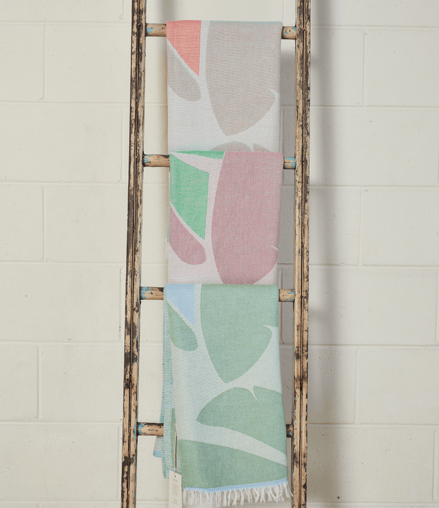 Pastel Coloured Turkish Beach Towels showcasing leaf patterns hanging on a rustic ladder.