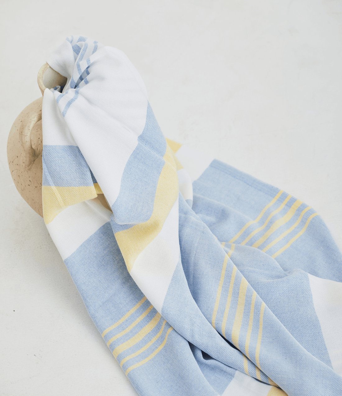 A lightweight peshtemal towel in light yellow and blue