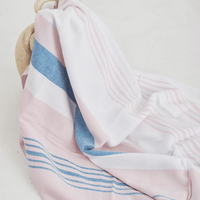 A lightweight peshtemal towel in light pink and blue