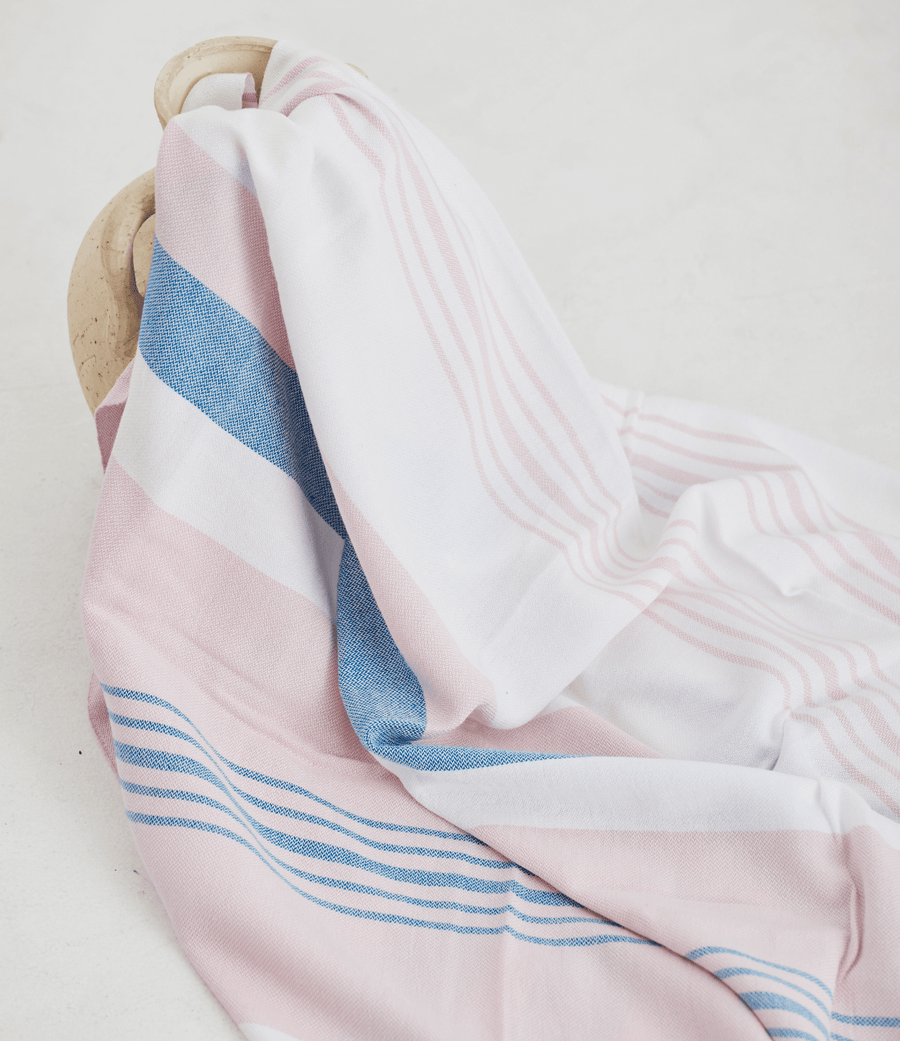 A lightweight peshtemal towel in light pink and blue