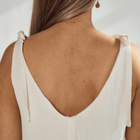 Back view of a soft cotton dress showcasing tied straps and a deep v-neckline, highlighting its elegant design.