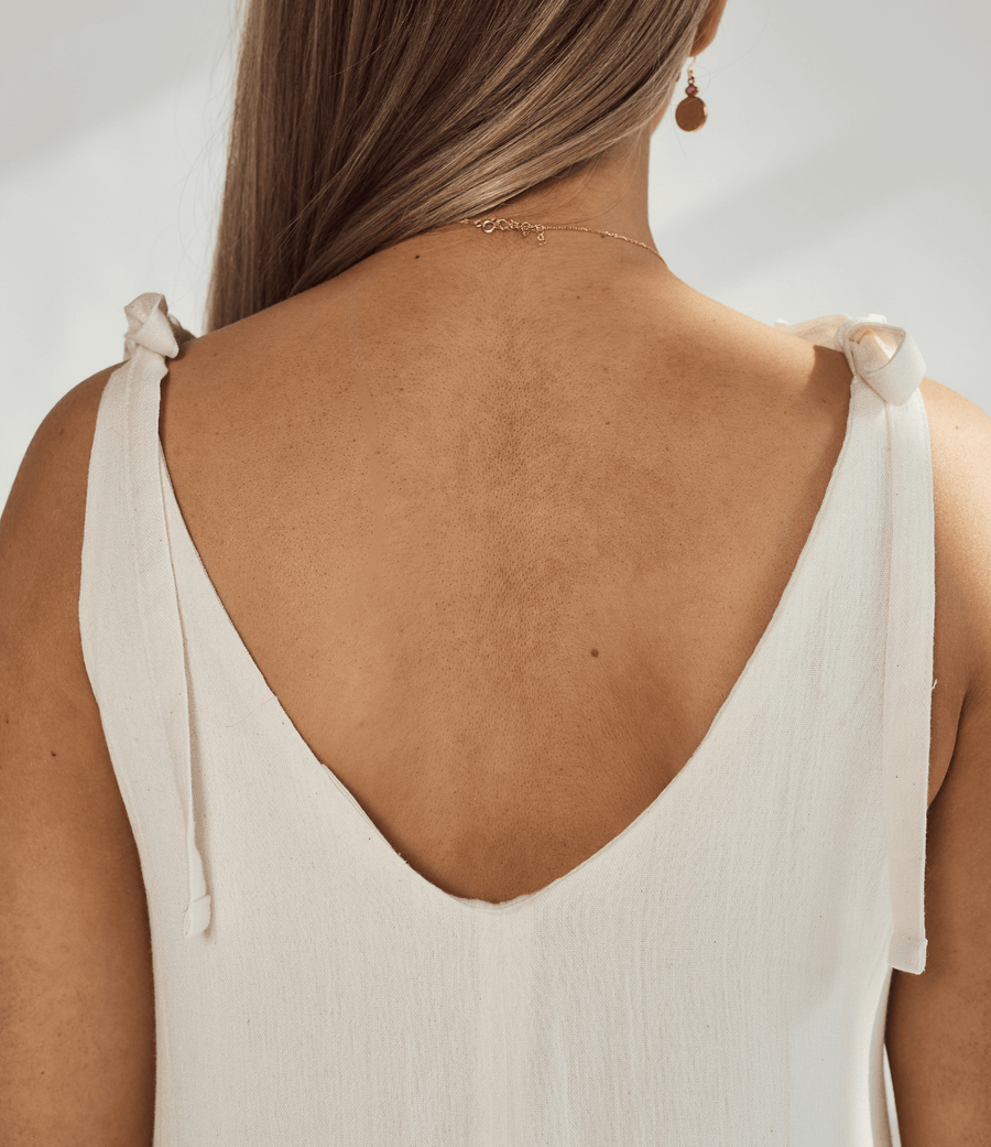 Back view of a soft cotton dress showcasing tied straps and a deep v-neckline, highlighting its elegant design.