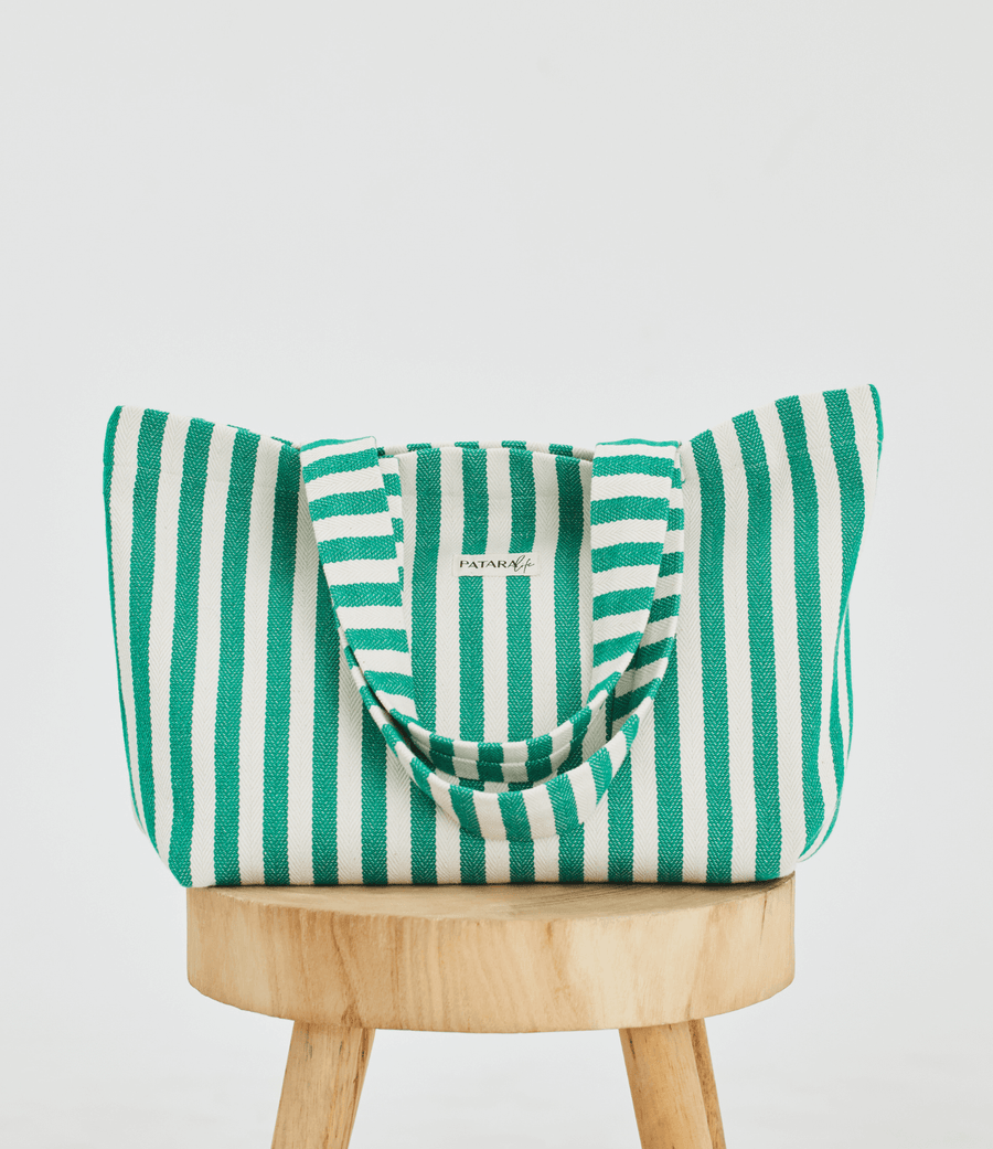 Herringbone woven linen tote bag in Green stripe on top of stool