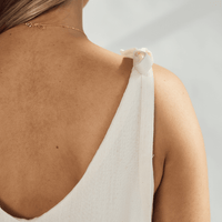 Close-up of the back of a soft cotton dress with tied straps and a graceful neckline.