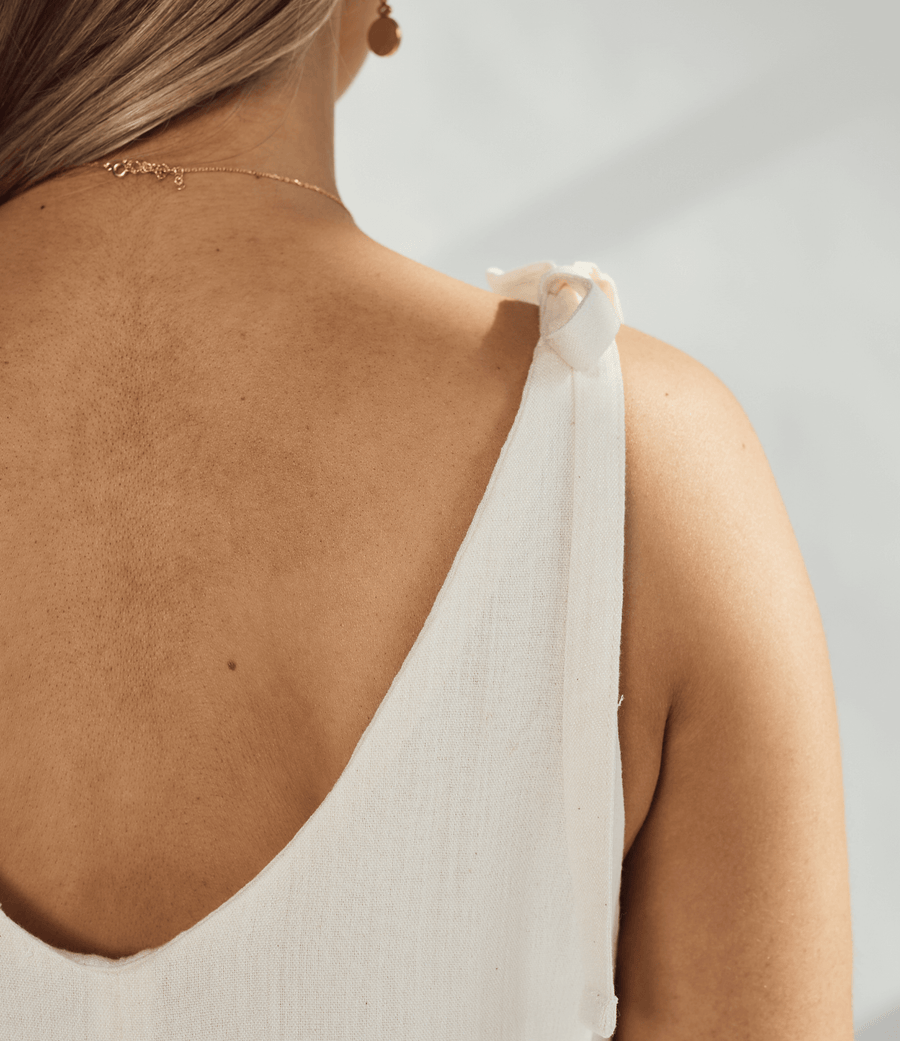 Close-up of the back of a soft cotton dress with tied straps and a graceful neckline.