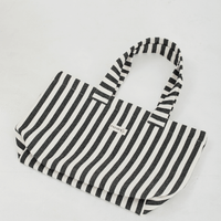 Herringbone woven linen tote bag in Black stripe layed flat on floor