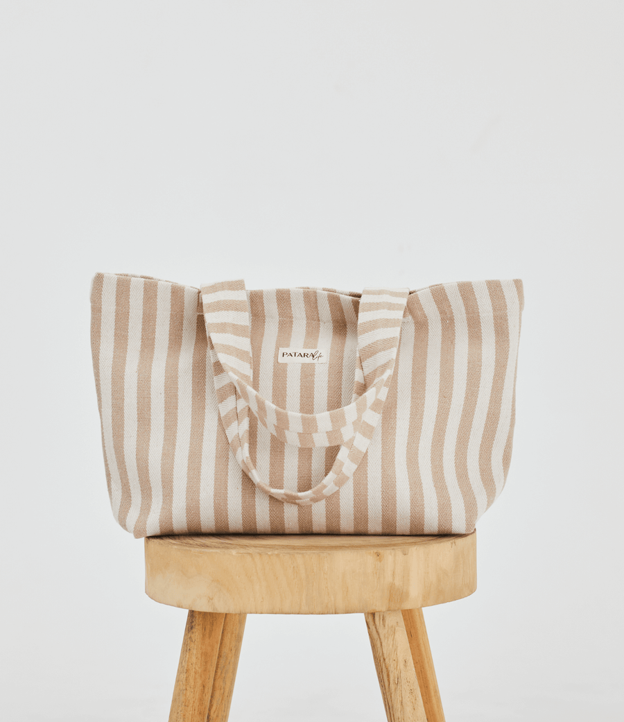 Herringbone woven linen tote bag in Color: Light Brown stripe on top of stool