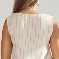Close-up of a person wearing a beige sleeveless top with thin vertical stripes on a light gray background.