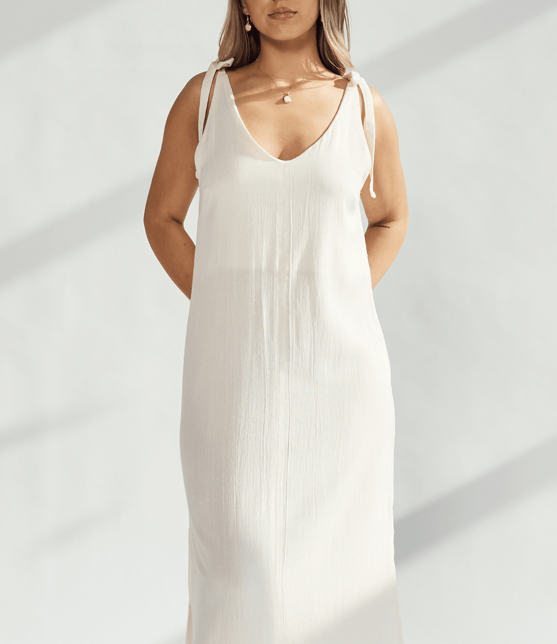 Elegant soft cotton dress with tied straps and subtle leg slits, perfect for refined and comfortable wear.