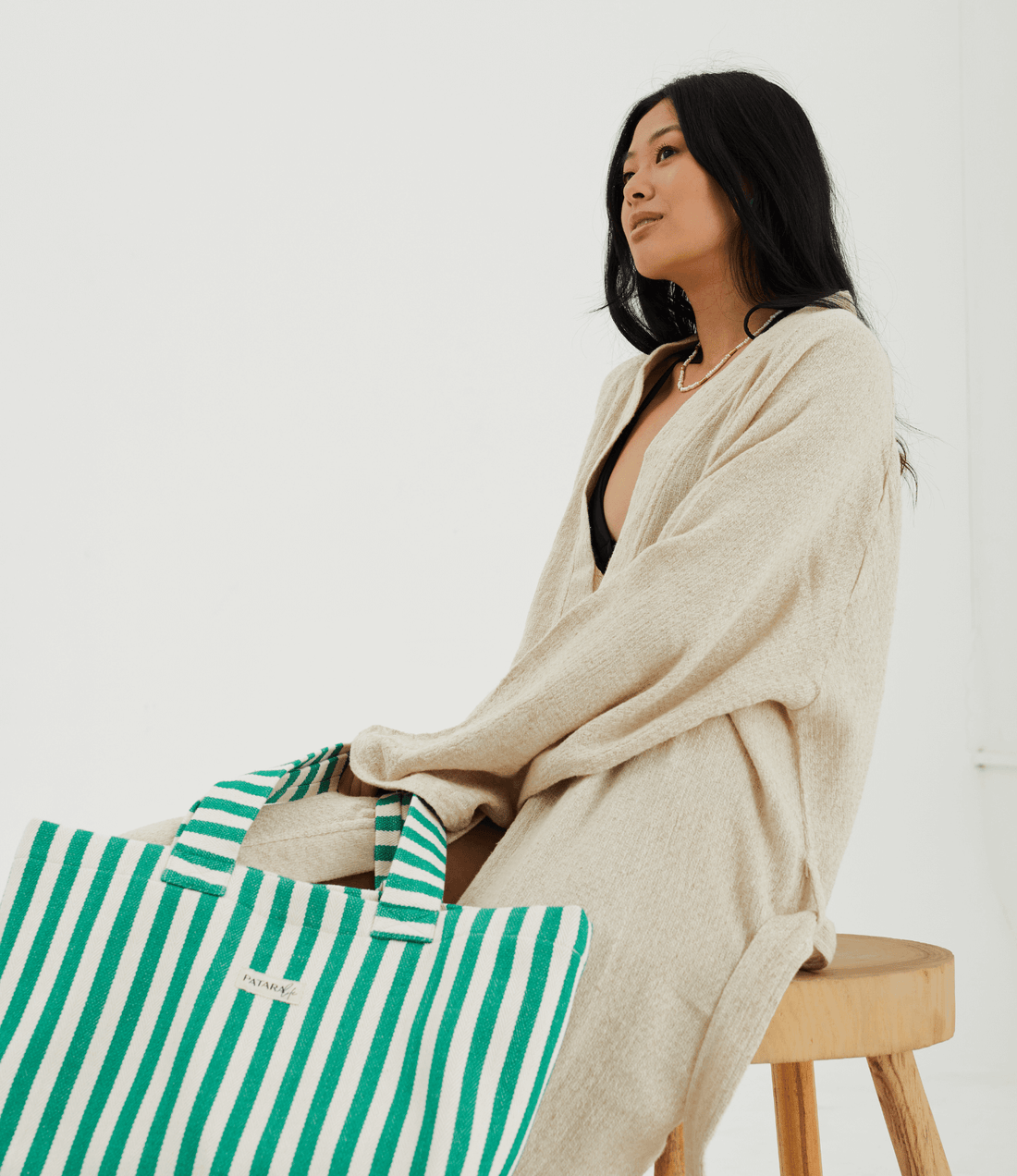 Herringbone woven linen tote bag in Green stripe resting against body