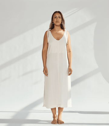 Model wearing a soft cotton dress with tied straps, showcasing a relaxed fit and elegant design.