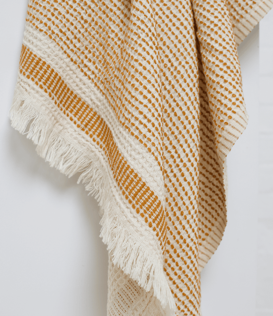 A dotted Turkish cotton "Kalkan" beach towel in mustard yellow