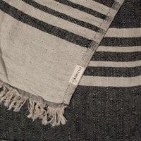 Close up of a black and beige linen & cotton premium throw layed flat