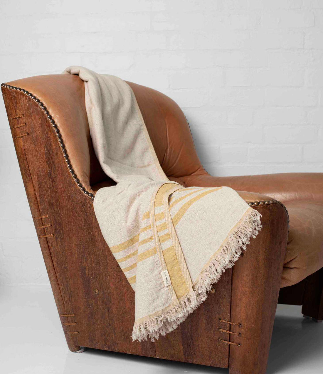 A yellow and beige throw draped over leather armchair